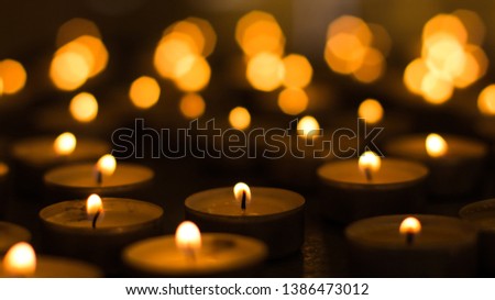 candles yellow fire illumination and unfocused bokeh effect background inside religion building in church service time twilight environment