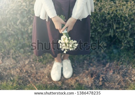 Hipster woman with a bouquet of snowdrops on the background of a natural parkland.