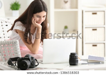 Young female photographer with laptop at home