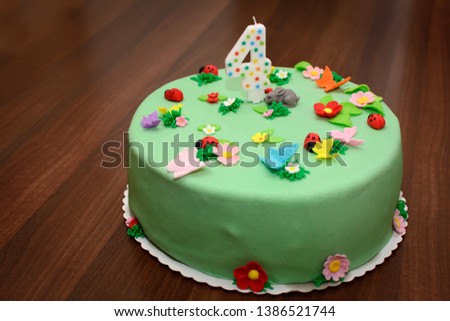 Colorful birthday cake with candle, decorated with figures of animals and flowers for kids party or celebration