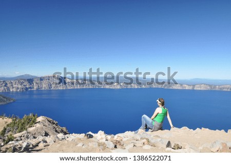 Young female Caucasian hiker in green tank top overlooking Crater Lake National Park, Oregon, USA
