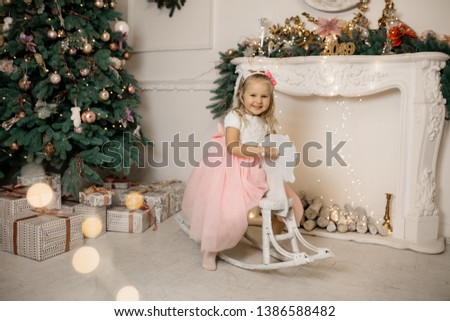 Little girl on toy horse near christmas tree