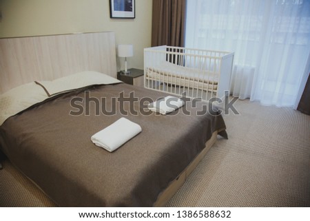 interior rooms with a balcony in the hotel, large double bed, cot, bedside table and a picture on the wall