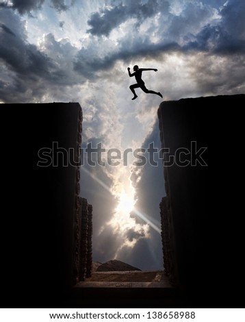 Man Silhouette jumping over the abyss at sunset cloudy sky background Royalty-Free Stock Photo #138658988