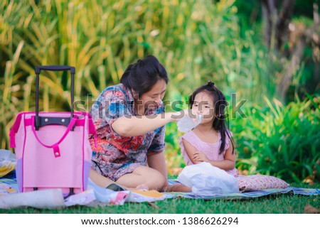cute little daughter and mother sitting in the park during a picnic