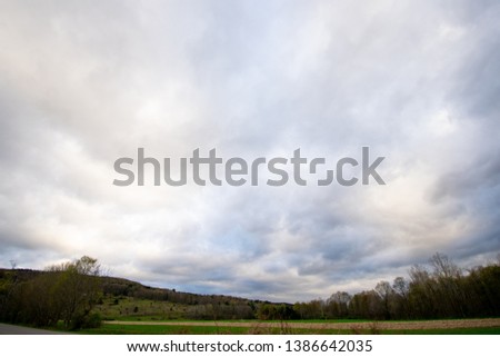 Ominous clouds hanging over a green landscape.