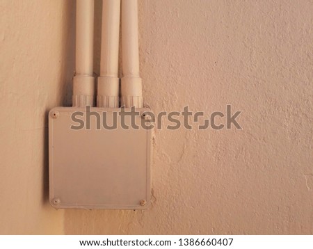 Electrical equipment box and yellow cement wall, cream background