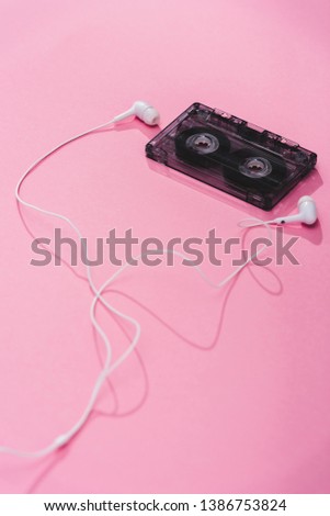 plastic vintage audio cassette with earphones on pink, music concept