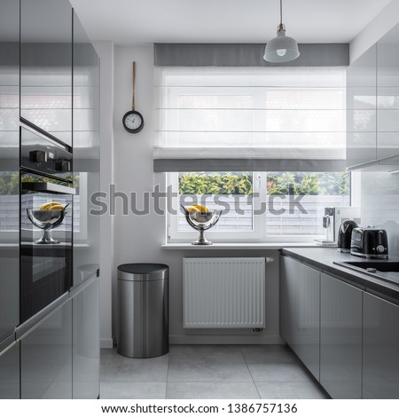 Modern, narrow kitchen with window and gray furniture Royalty-Free Stock Photo #1386757136