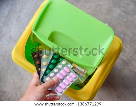 throwing away expired medicine pills in pack in trash can Royalty-Free Stock Photo #1386771299