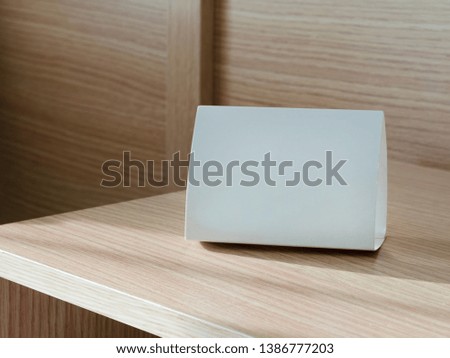 White sign cardboard with copy space on a light brown shelf.