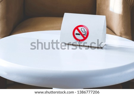 White cardboard sign No smoking on a white round table. Hotel indoor