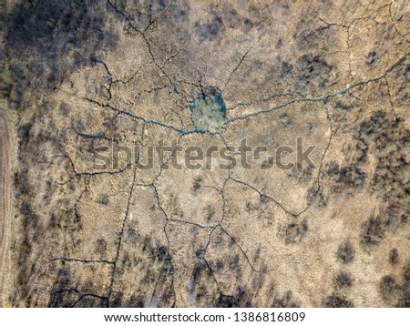 aerial view of small country river bed wavy in spring time in countryside with dry grass and some bushes. fields texture