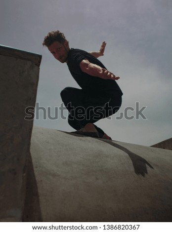 Male movement artist dancing in an empty skatepark, casting a shadow into the skate pool, from where the photo is shot.