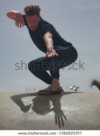 Male movement artist dancing in an empty skatepark, casting a shadow into the skate pool, from where the photo is shot.