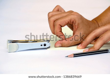 A young woman Office worker tries to bring out the staples from the paper with the fingernails by not using specific equipment that came with a paper stapler on white background.