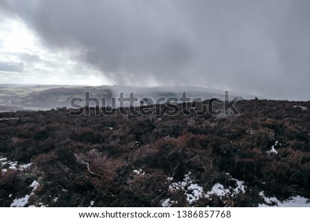 Beautiful moody landscape picture of the Peak District National Park with a heavy storm clouds