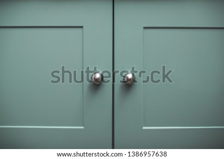 conceptual photo of the doors of a modern blue-green cabinet with chrome handles and milling