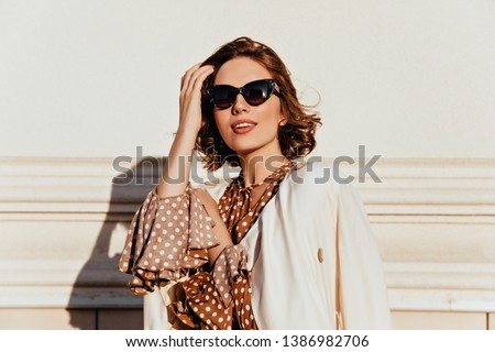 Lovely woman in vintage outfit expressing interest. Outdoor shot of glamorous happy girl in sunglasses. Royalty-Free Stock Photo #1386982706