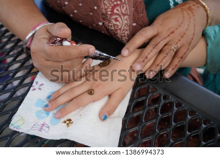 Hands applying Indian Henna tattoo on a another person. Photo taken in San Jose, California on April 19, 2019.