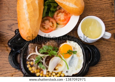 Vietnamese breakfast of baguette (banh mi), tea, beef with gravy (Bo ne pate) and corned beef with egg (trung op la)