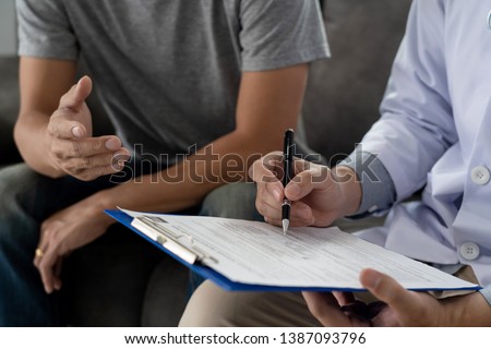 Geriatric doctor or geriatrician concept, Doctor visiting with patient in room and hearing serious disease diagnose writing on clipboard while consulting a man at home   Royalty-Free Stock Photo #1387093796
