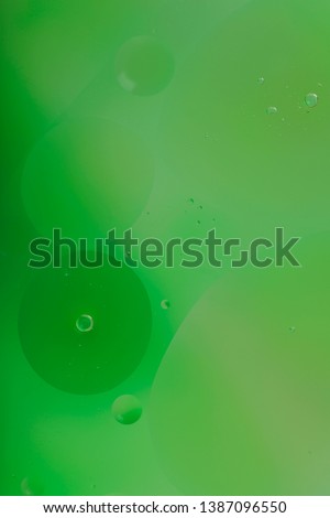 Blurred abstract background. Macro shot of oily liquid. Green circles and wavy lines of different sizes. Blur, vertical, a lot of free space for text, nobody, macro. Concept of design.