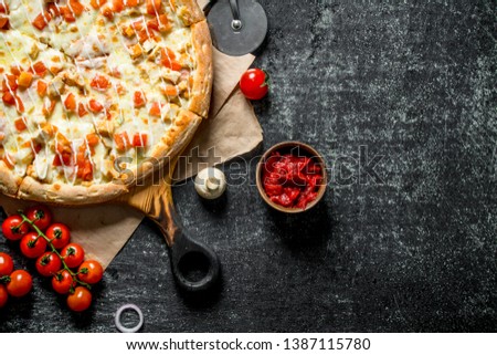 Hot pizza on paper with cherry tomatoes. On dark rustic background