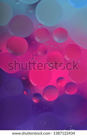 Blurred abstract background. Macro shot of oily liquid. Circles and wavy lines of different sizes in pink, violet and blue. Blur, vertical, a lot of free space for text, nobody, macro.