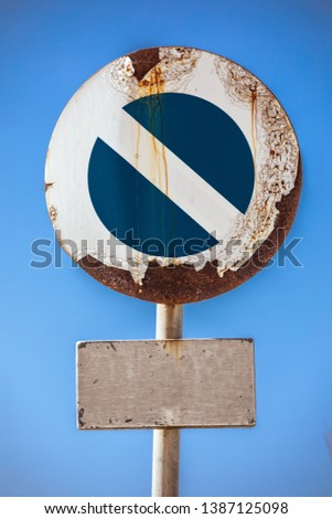 Road sign prohibiting access, at the bottom a sign with empty space to customize. In the background a blue sky. The road sign appears damaged by the weather and rusted.