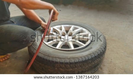 Car mechanic patching a tire. Nut screwing a car hub. Jack for lifting the vehicle.