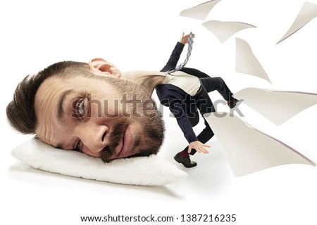Break night dreams as a glasses. Big head on small body lying on the pillow. Man in black suit cannot wake up 'cause headache and overslept. Concept of business, working, hurrying up, time limits.