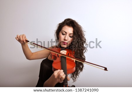beautiful woman with black hair playing violin Royalty-Free Stock Photo #1387241090