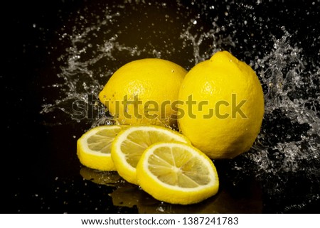 Lemon with drops and splashes of water on a black background