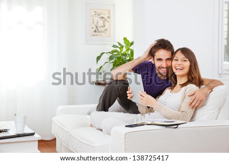 Young couple with digital tablet at home. Happy young couple smiling Royalty-Free Stock Photo #138725417