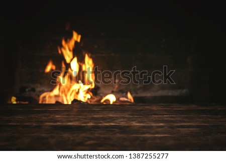 Empty table with a copy space for food for example over a burning fire in a brick fireplace.