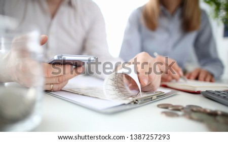 Young family man and woman checking household budget expenses using mobile smartphone app against background house. Royalty-Free Stock Photo #1387257293