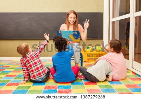 Woman as a teacher and children have fun together while reading aloud in kindergarten or daycare