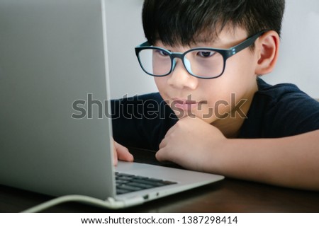 An asian pre-teen (tween) boy wearing Blue Light Blocking Glasses while coding with his laptop to protect his eyes from Computer Vision Syndrome: KIDS health, dry eyes concern - Close up Royalty-Free Stock Photo #1387298414