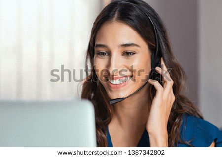 Smiling woman using laptop while talking to customer on phone. Consulting corporate client in conversation with customer using computer. Service desk consultant talking in a call center. Royalty-Free Stock Photo #1387342802