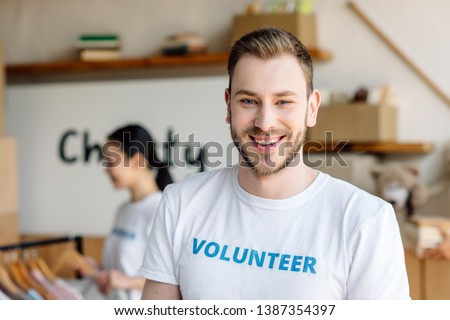 selective focus of handsome young man in white t-shirt with volunteer inscription
