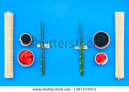Japanese food cooking set with soy sauce, ginger, bamboo sticks for sushi on blue background top view
