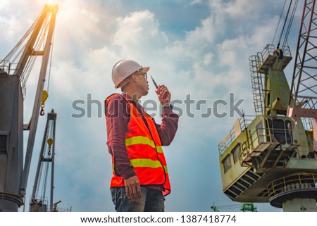 foreman, supervisor, worker, loading master in works at job site, control to the teamwork by walkie talkie radio for job done in the same direction, working at risk and high level of insurance Royalty-Free Stock Photo #1387418774
