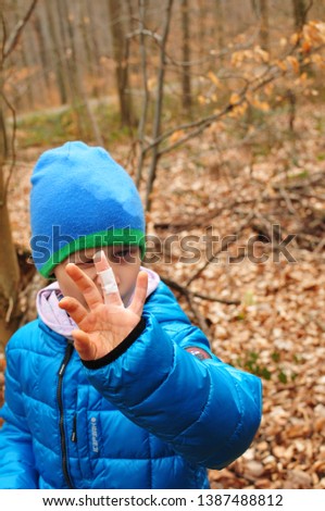 boy finds a cache during geocaching and shows his injured finger with plaster in the camera