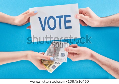 partial view of man giving bribe for vote to woman on blue background