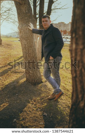Man standing beside trees in sunny day
Portrait of young man in casual clothes posing among trees on background of town and looking at camera