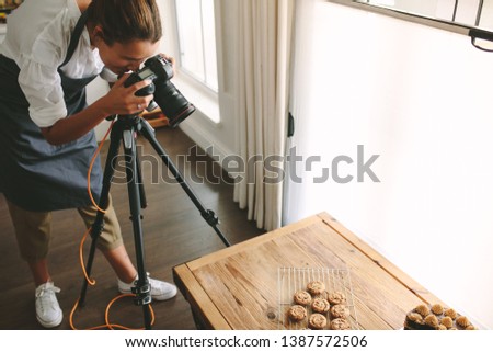 Female chef taking pictures of dessert on table with dslr camera mounted on tripod. Female taking pictures of sweet food for her blog.