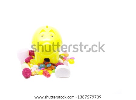 piggy bank and multi colored sugar candy in white background with space for text