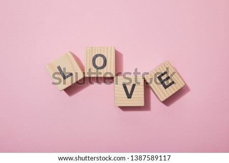 top view of wooden cubes with letters on pink surface