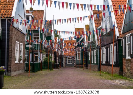 Typical dutch street in fishing village Marken in the Netherlands decorated with small colorful pennant garland on the rope crossing the street of traditional houses 